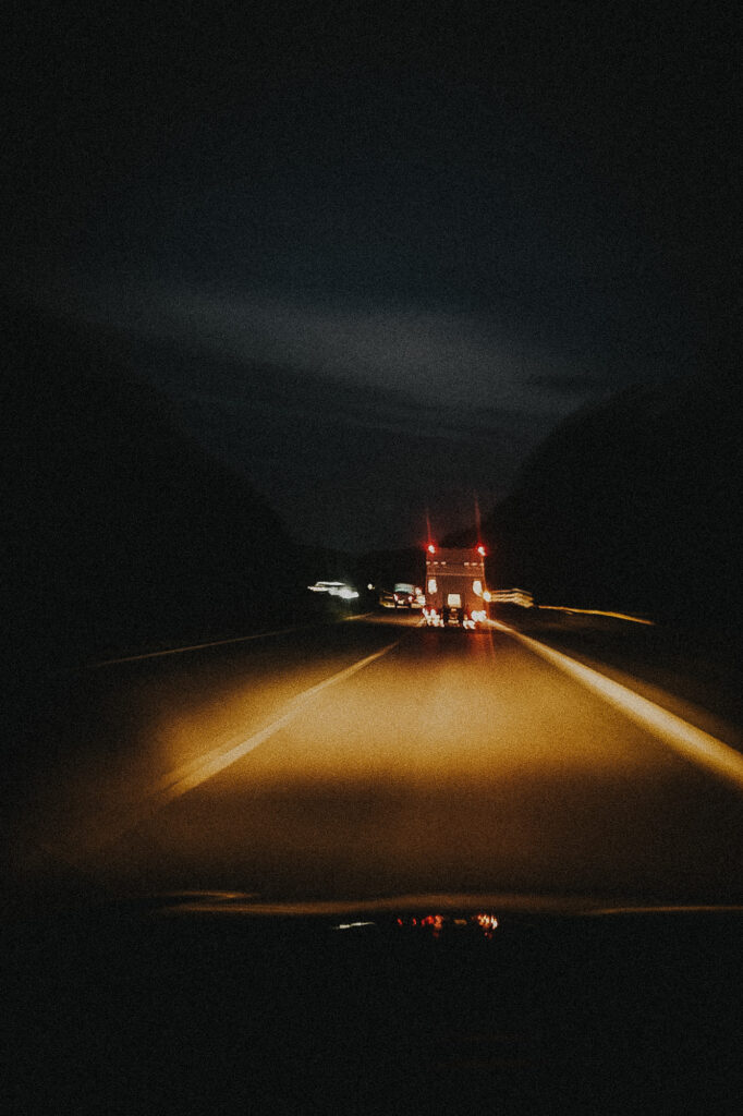 Blick durch die Windschutzscheibe auf die Rücklichter eines Lastwagens auf nächtlicher Landstraße