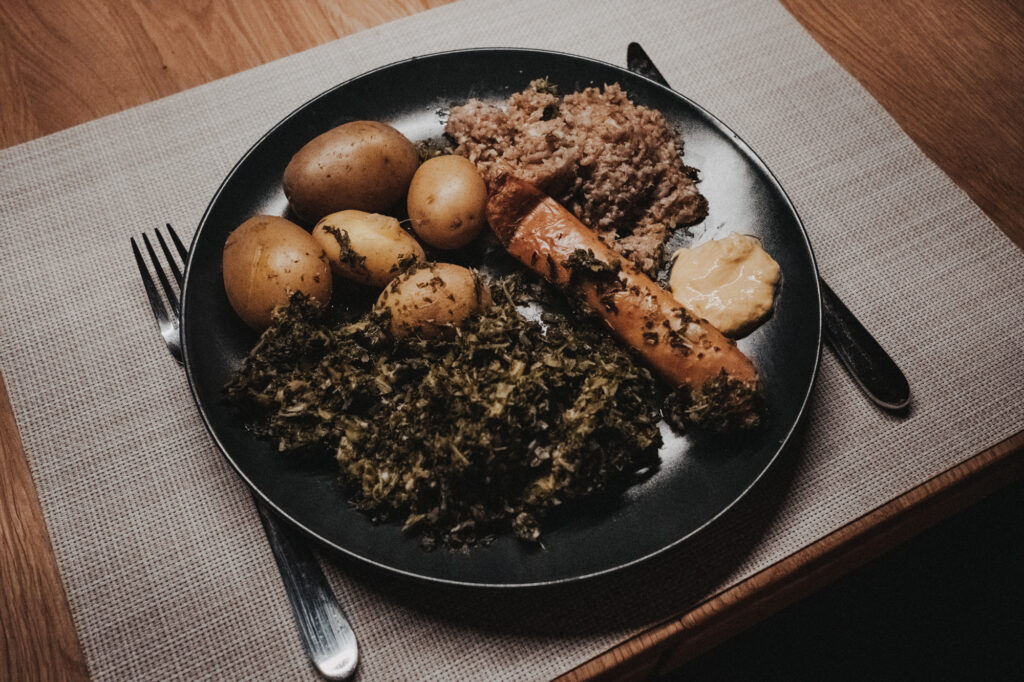 Teller mit Grünkohl, Pinkel, Kartoffeln und Senf
